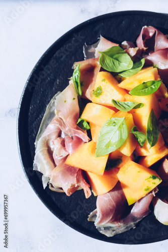 Italian style salad with prosciutto, melon and basil