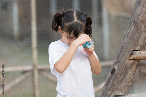 Child girl using looking through binoculars at playground outdoors © amorn