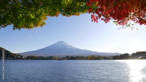 Beautiful autumn time at Lake Kawaguchi, iconic view of mountain, water and multi-colored maple leaves. Bright evening sun with shimmering reflection on water surface photo