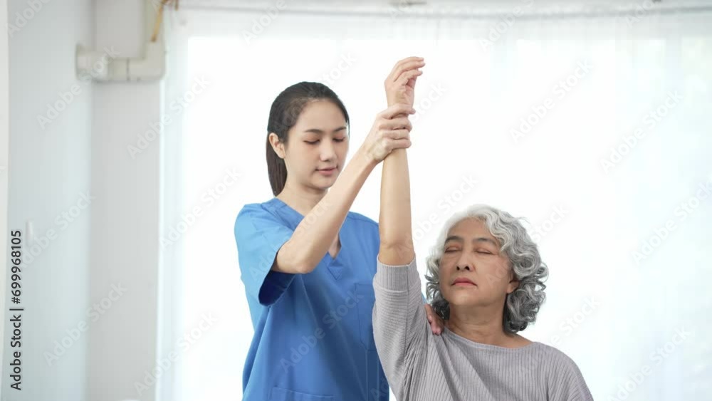 Physiotherapist doing physical therapy to an elderly Asian woman examining the treatment of a female patient's injured arm to rehabilitate the painful arm with a female doctor Health care concept Physiotherapist doing physical therapy to an elderly Asian woman examining the treatment of a female patient's injured arm to rehabilitate the painful arm with a female doctor Health care concept