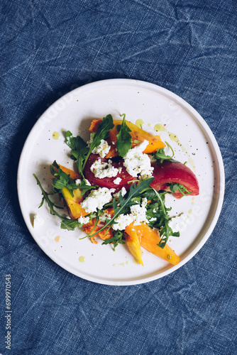 Healthy salad with different types of tomatoes, sweet potato, feta cheese and arugula