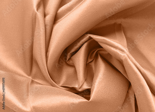 Peach fuzz is the color of the year 2024. Silk fabric folded with beautiful curves with shadows.