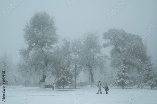 woman mother and a child son walk through the Independence Park in Shymkent in Kazakhstan in winter with snow and fog