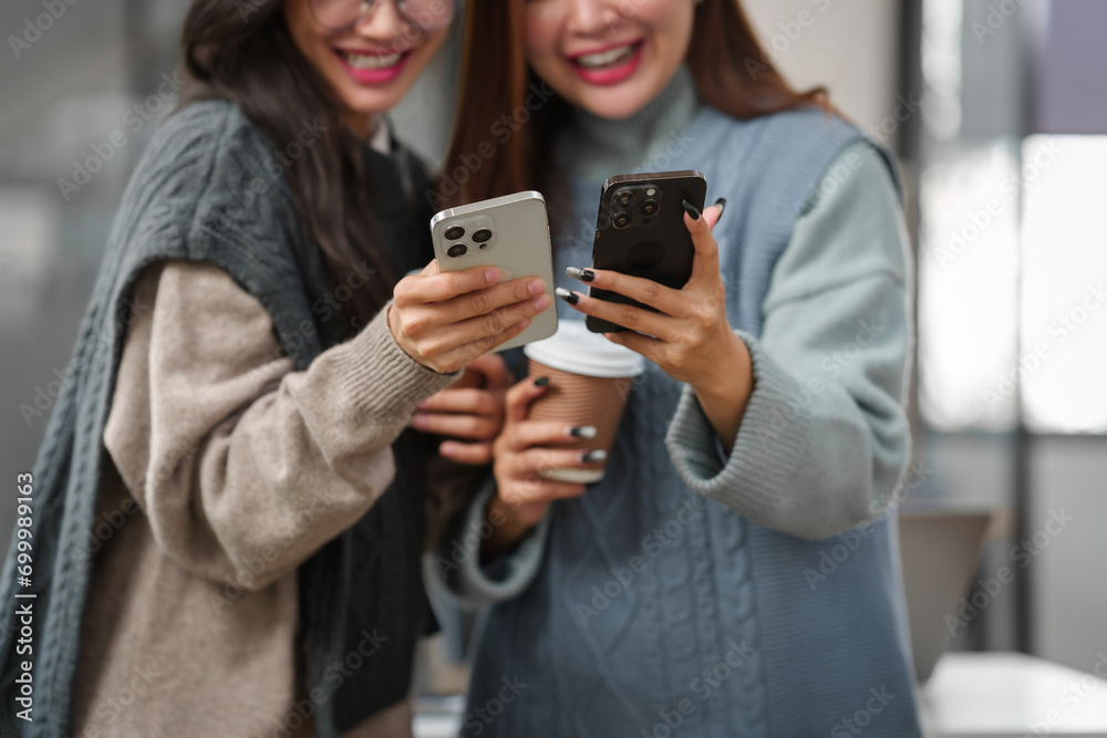 Two Asian individuals, possibly friends, studying together with a tablet and a laptop on the table.