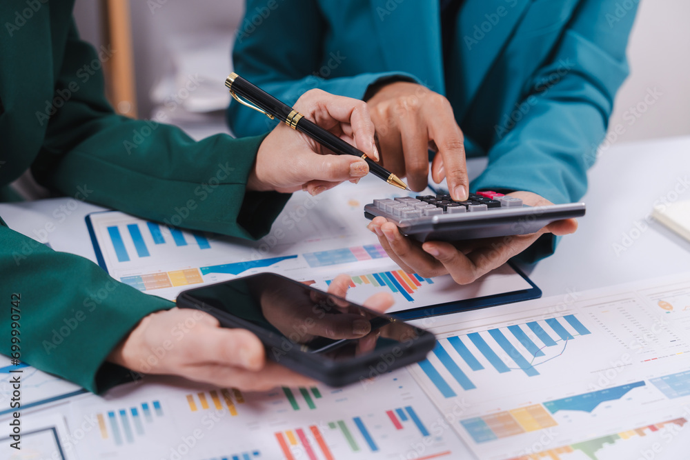 Two professionals are calculating finances, one using a calculator and the other taking notes, surrounded by colorful graphs and charts. Two professionals are calculating finances, one using a calculator and the other taking notes, surrounded by colorful graphs and charts.
