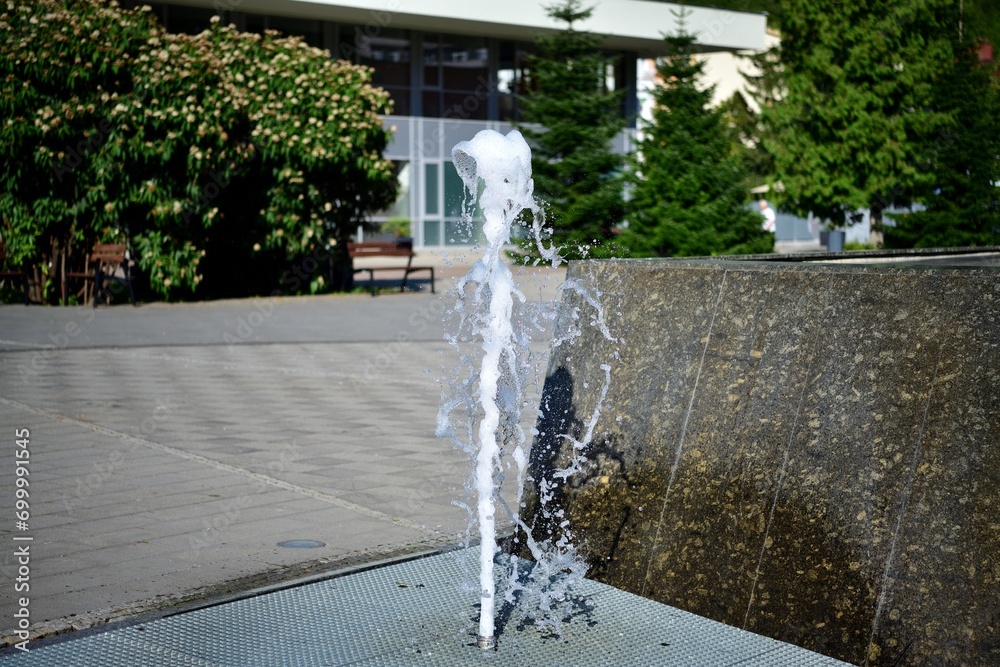 The urban white water fountain sprays up a geyser of water in the summer