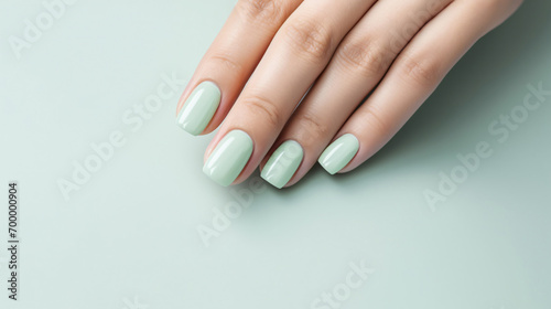Glamour woman hand with mint green nail polish on her fingernails. Green nail manicure with gel polish at luxury beauty salon. Nail art and design. Female hand model. French manicure.