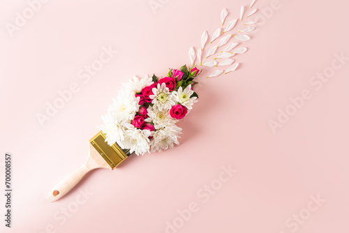 Brush paints with flowers, spring concept on pastel pink background. Minimal nature flat lay. A copy space