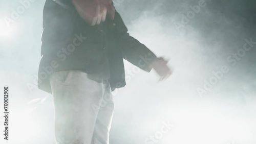 Unrecognizable man rapping and gesticulating with hands on a smoke-filled stage photo