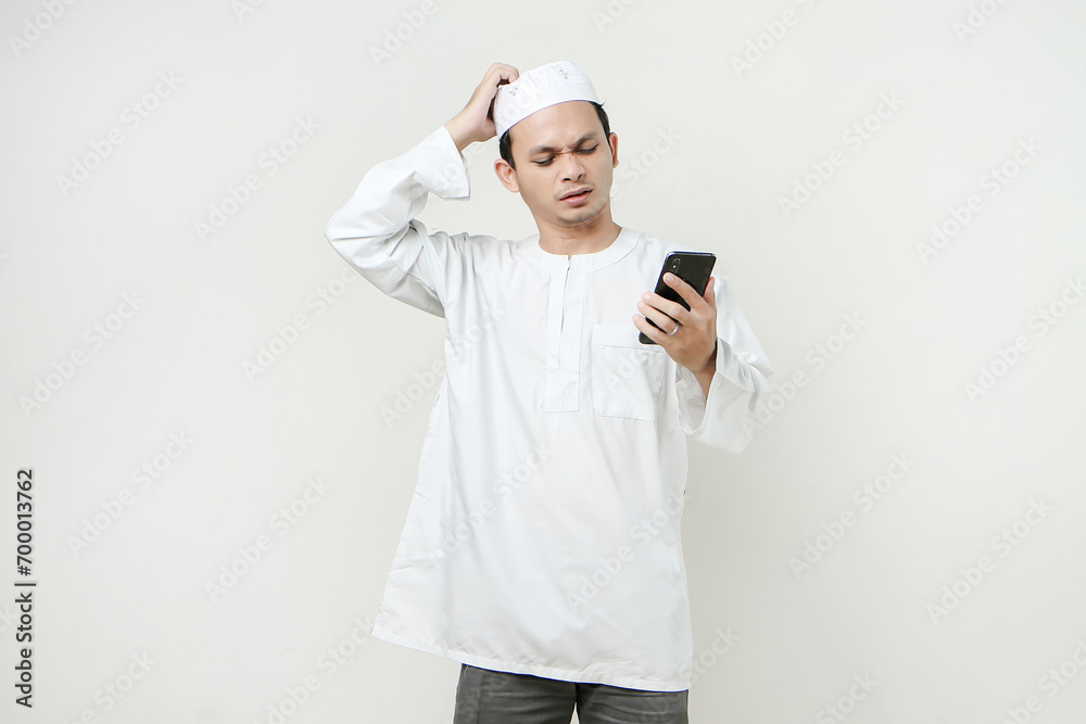 muslim man holding mobile phone and give stressful frustated expression. People religious Islam lifestyle concept. celebration Ramadan and ied Mubarak. on isolated backgroun. muslim man holding mobile phone and give stressful frustated expression. People religious Islam lifestyle concept. celebration Ramadan and ied Mubarak. on isolated backgroun.