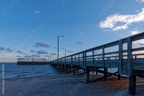 The setting suns Orange light falling on the sand beneath the Pier at Palacios on the Gulf Coast of Texas close to the City of Rockport.