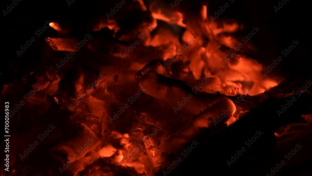 Close up of glowing burning embers in fire pit on black background Close up of glowing burning embers in fire pit on black background