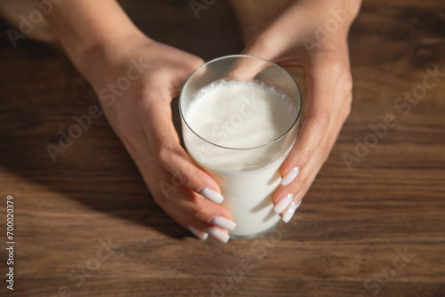Hand holding a glass of milk on the table.