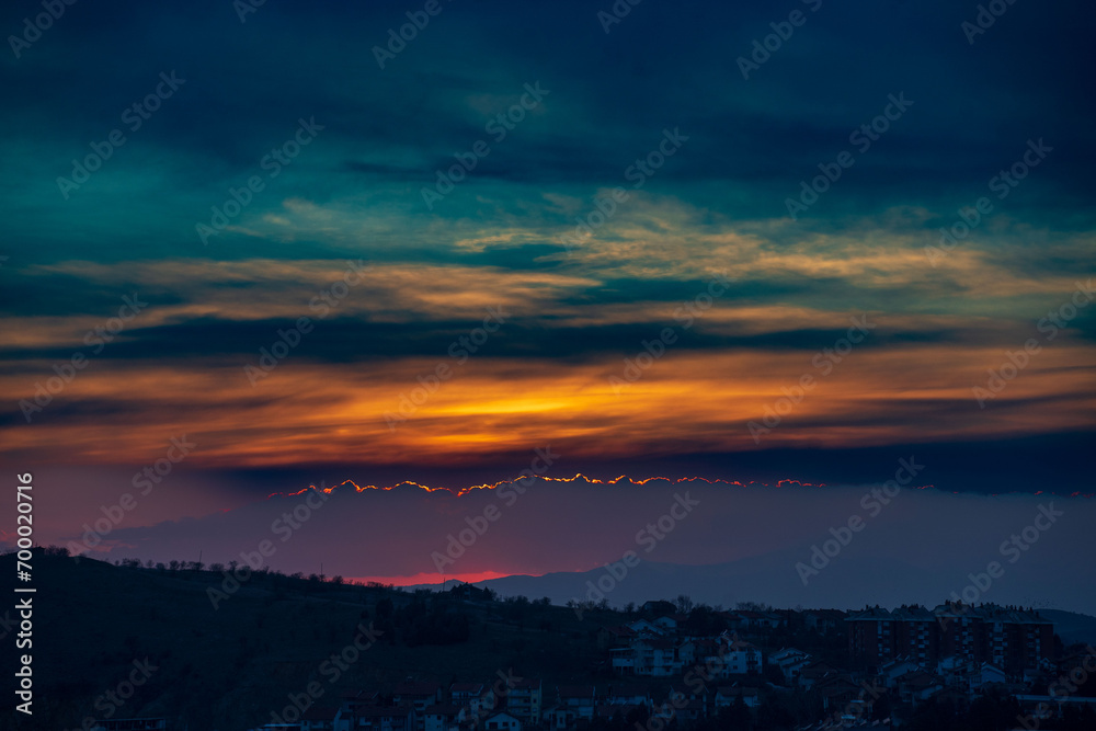 Dramatic sunset time with colorful clouds, above the city. Magenta, orange and blue colors.