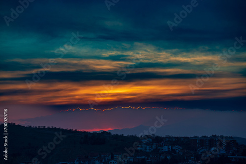 Dramatic sunset time with colorful clouds, above the city. Magenta, orange and blue colors.