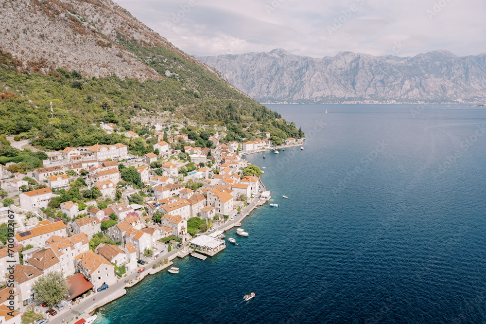 Ancient houses with red roofs at the foot of green mountains. Perast, Montenegro. Drone