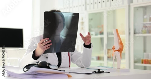 Doctor traumatologist examining xray of knee joint near anatomical model 4k movie slow motion photo