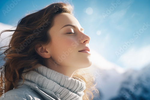 close-up portrait of a woman with closed eyes in the rays of the sun on a sunny winter day in the mountains