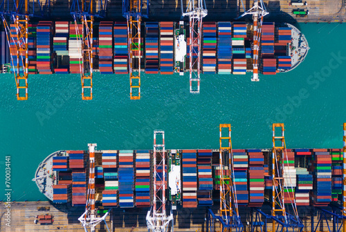 Global transportation and logistic business. Aerial top view over international containers cargo ship at industrial import-export port prepare to load containers with big container loader ship.