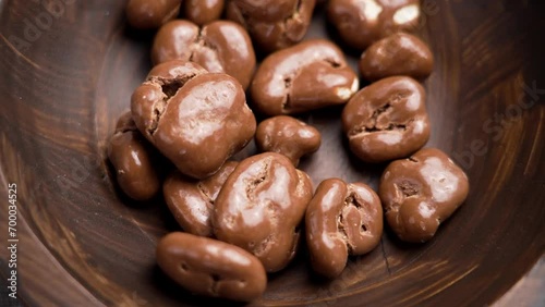 Chocolate covered walnut. Delicious nutritious nut candies falling into a rotating wooden bowl close up. Slow motion