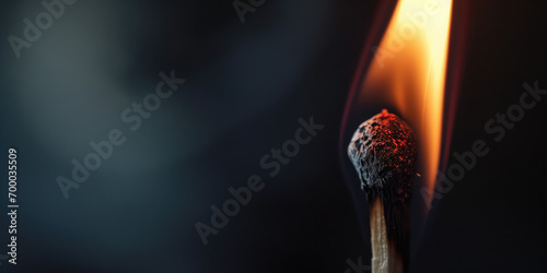 A close-up of a burning wooden match on black background. Match head with burning gray at the end, flames, copy space. Creative banner of energy, fuel industry. photo