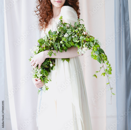 Bride in delicate gown with unusial bouquet of small white flowers photo