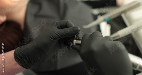 Close-up of dentist s hands holding dental tools and toothpaste. The use of sterile materials and the process of professional teeth cleaning in a dental clinic.