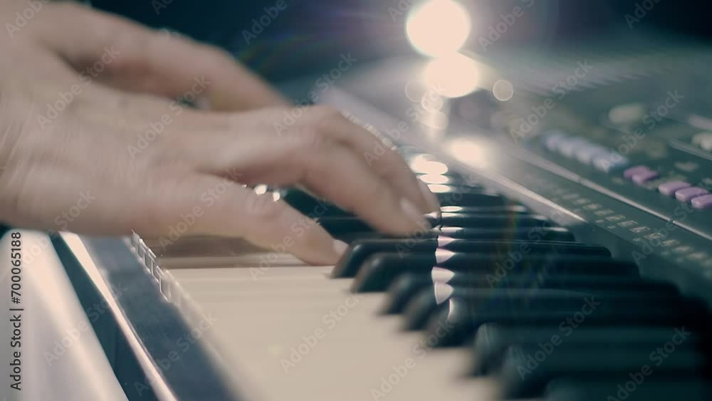 Female hands playing on a synthesizer keyboard (piano) shining in the backlight. Shot in motion. Closeup. Macro. Shallow depth of field