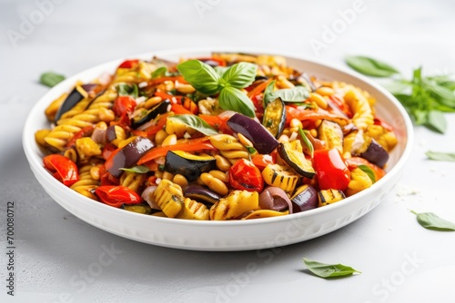 Close up view of ratatouille pasta salad on a plate, with a white stone background.