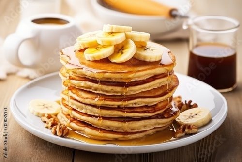 Healthy breakfast with oatmeal banana pancakes fresh banana slices walnuts and honey on a white wooden surface alongside a cup of tea Copy space available