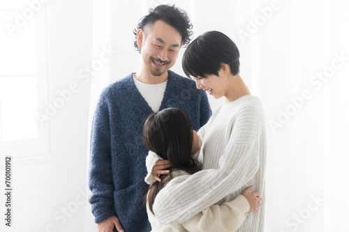 メインビジュアルにも！逆光の白い中、娘をハグして愛する父親と母親の子育てのイメージのクローズアップ