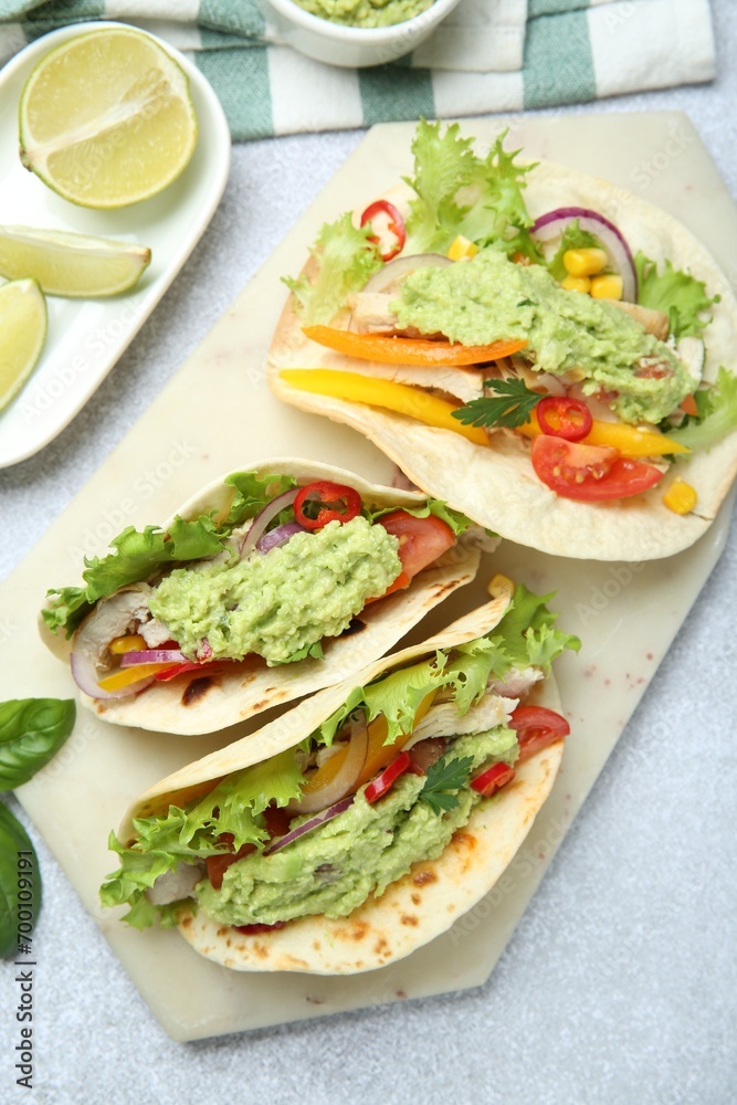 Delicious tacos with guacamole, meat and vegetables on light grey table, flat lay Delicious tacos with guacamole, meat and vegetables on light grey table, flat lay