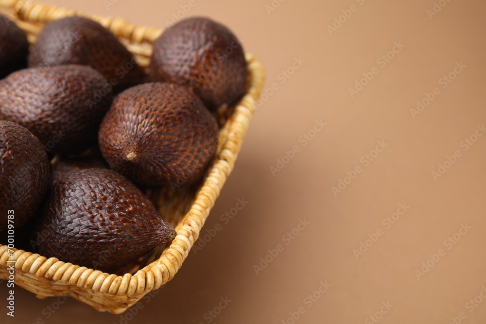 Delicious salak fruits in basket on pale brown background, closeup. Space for text