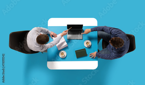 Creative collage. Aerial view of two confident man, entrepreneurs sitting at common table with document and laptop and discussing work tasks. Concept of business lunch, morning meeting, briefing. Ad photo
