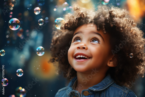 Happy afro-american little girl excited looking up in the bubbles