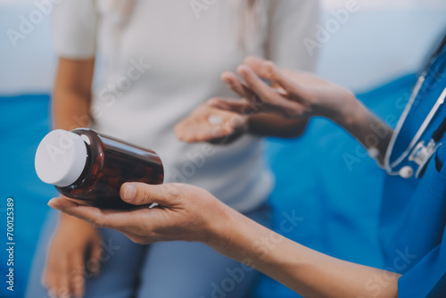 Asian woman nurse holding a medicine bottle and telling information to Asian senior woman before administering medication. Caregiver visit at home. Home health care and nursing home concept. photo