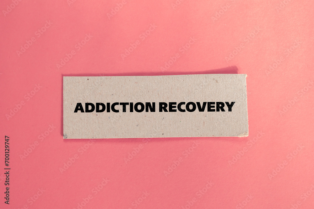 Obraz premium Addiction recovery lettering on ripped paper piece with color background. Conceptual photo. Top view, copy space.
