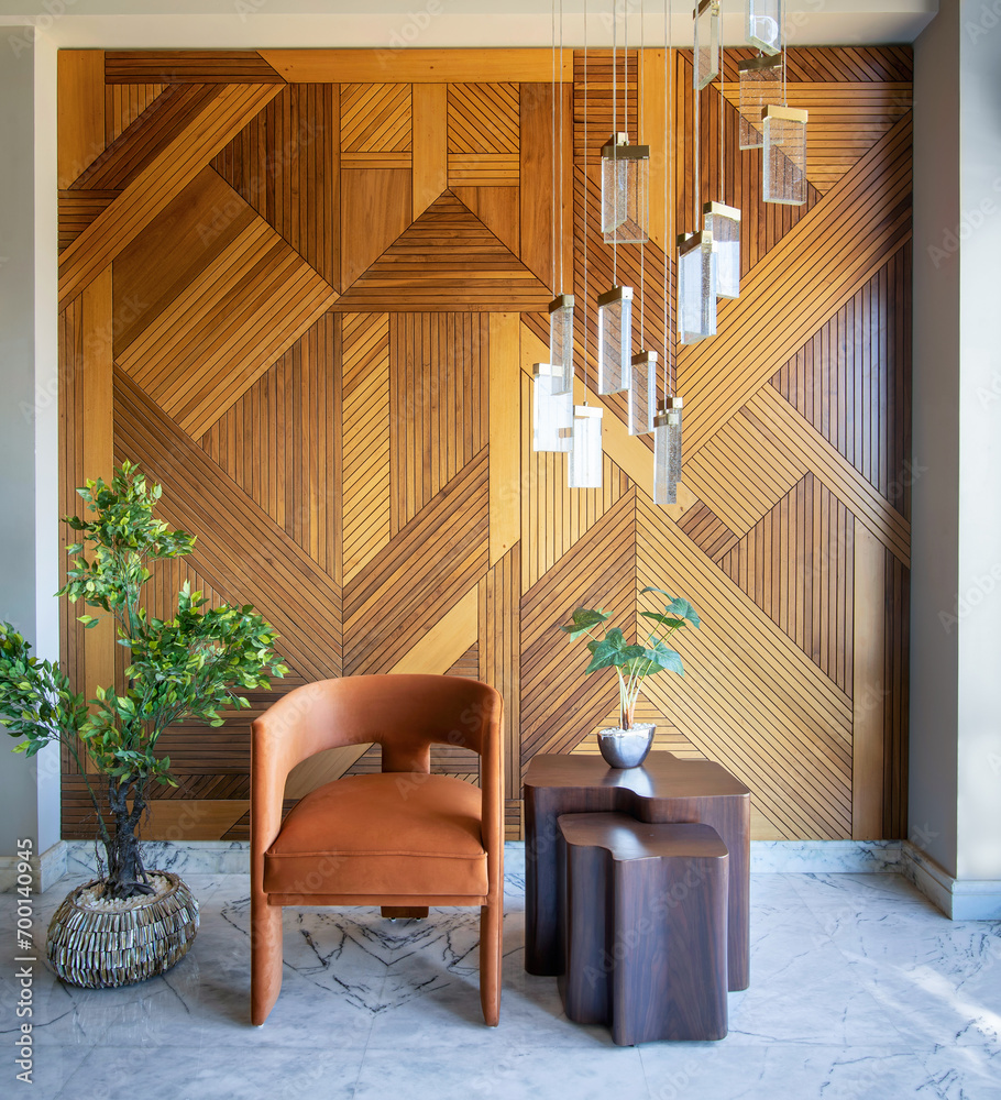 Simple and elegant image of a modern design fashionable orange chair and wooden coffe table in front of a decorated wood cladding wall, with hanging chandelier and a potted plant Simple and elegant image of a modern design fashionable orange chair and wooden coffe table in front of a decorated wood cladding wall, with hanging chandelier and a potted plant