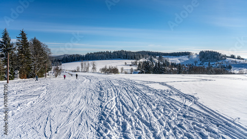 Panoramic winter landscape at Severak ski resort and many cross country skiers in Hrabetice, Jizera Mountains, Czechia