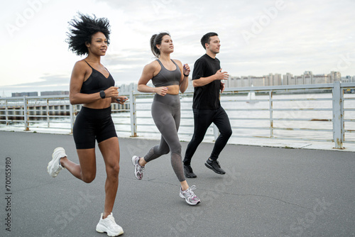 A group of people friends training running together in sports sneakers, runners training outside.