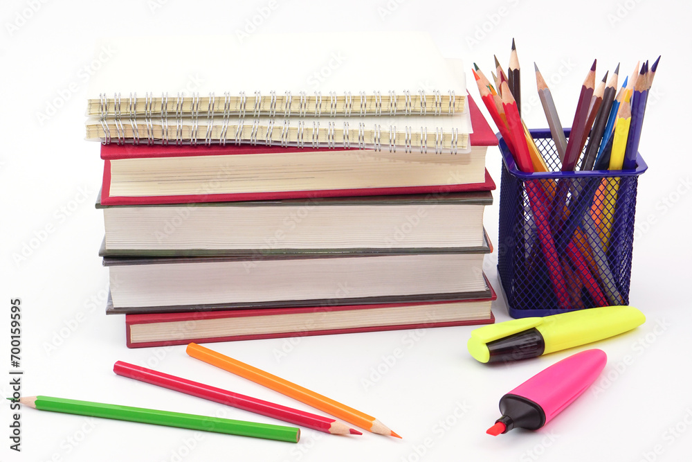 Fototapeta premium Crayon or colored pencils in box with side stack of books and school supplies on with background. Learning, study and office equipment concept.