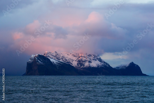 Purple clouds above a mysterious island covered in snow in the ocean
