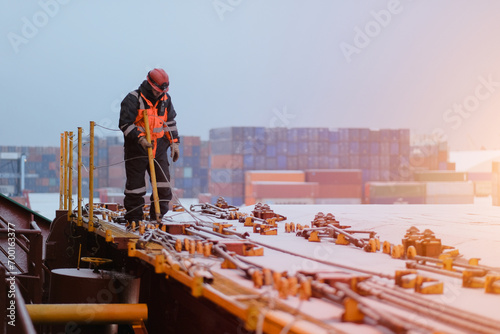 A Seafarer Walking On Deck Wearing Protective Safety Clothes and Distributing The Safety Handrails Before The Commencement Of Cargo Operations In The Port photo