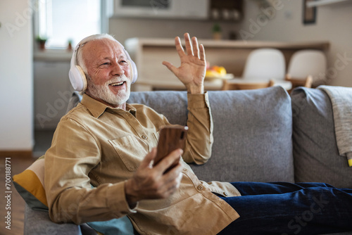 Phone, senior man and watch music video, streaming podcast and reading happy story, news article or retirement blog. Home, smartphone and elderly person with headphones, relax and listening to song.