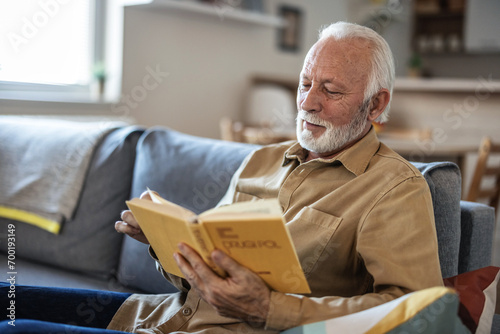 Senior men enjoying time at home by reading his favorite book. photo