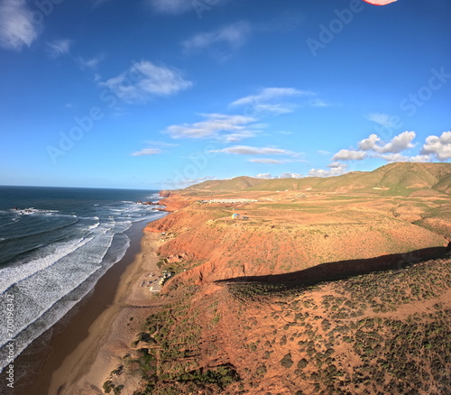 beauty of paragliding flying over scenic seaside landscape,sand dunes and mountain terrain,aerial apnorama landscape view,paragliding pilot with his paraglider wing,aerial extreme sports,action camera photo