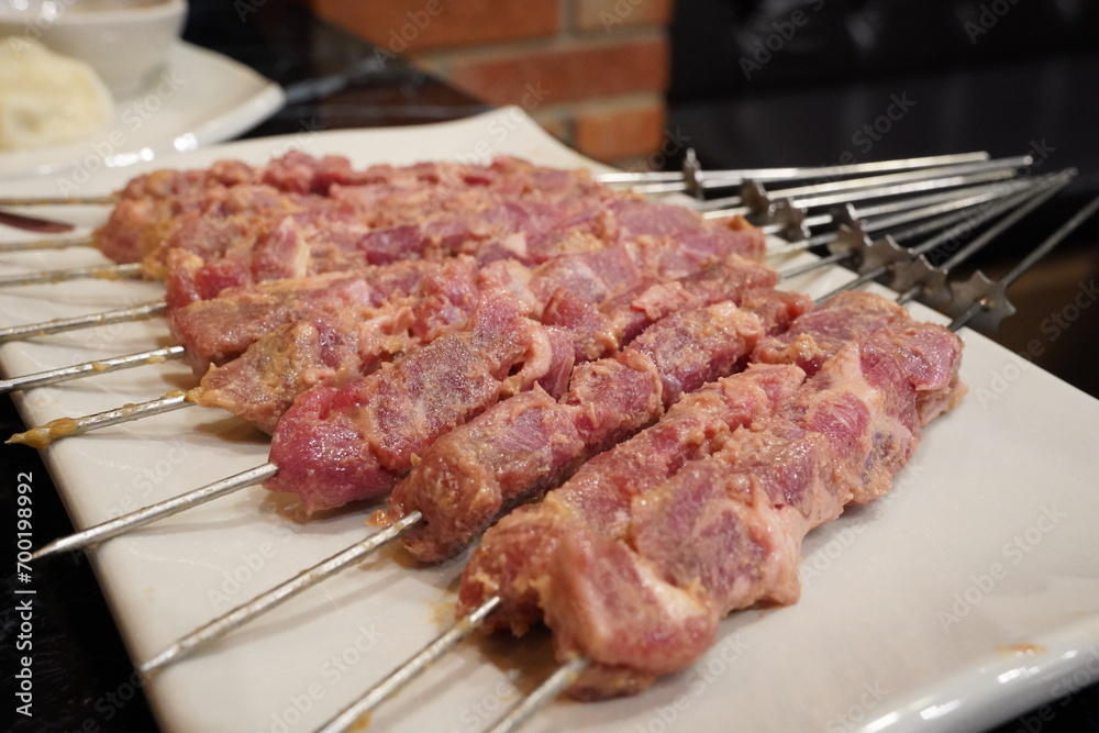 Raw, uncooked lamb skewers are served. Raw, uncooked lamb skewers are served.