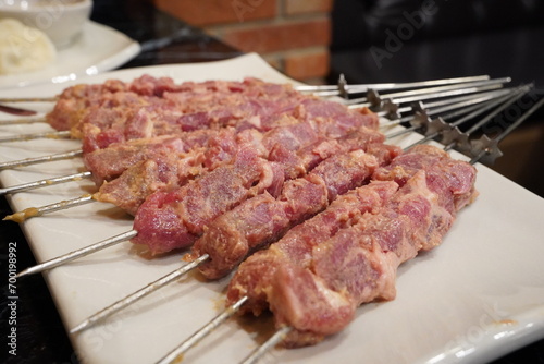 Raw, uncooked lamb skewers are served.