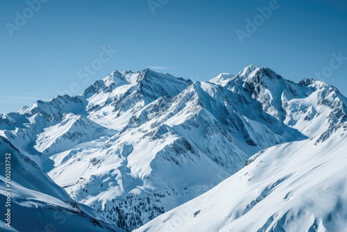 Snow-covered mountain peaks against a clear blue sky in winter.