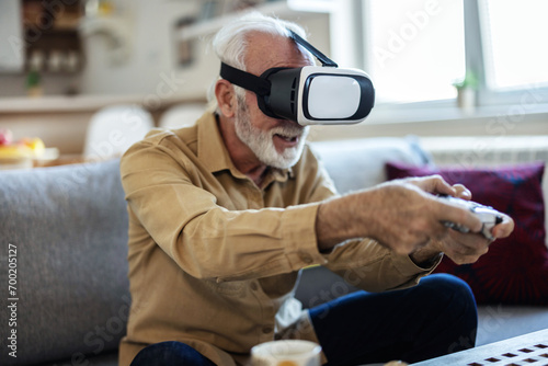 Vr, gaming and senior man in virtual reality in home on sofa in living room, laughing and having fun. 3d metaverse, esports gamer and happy retired male playing futuristic games with controller. photo